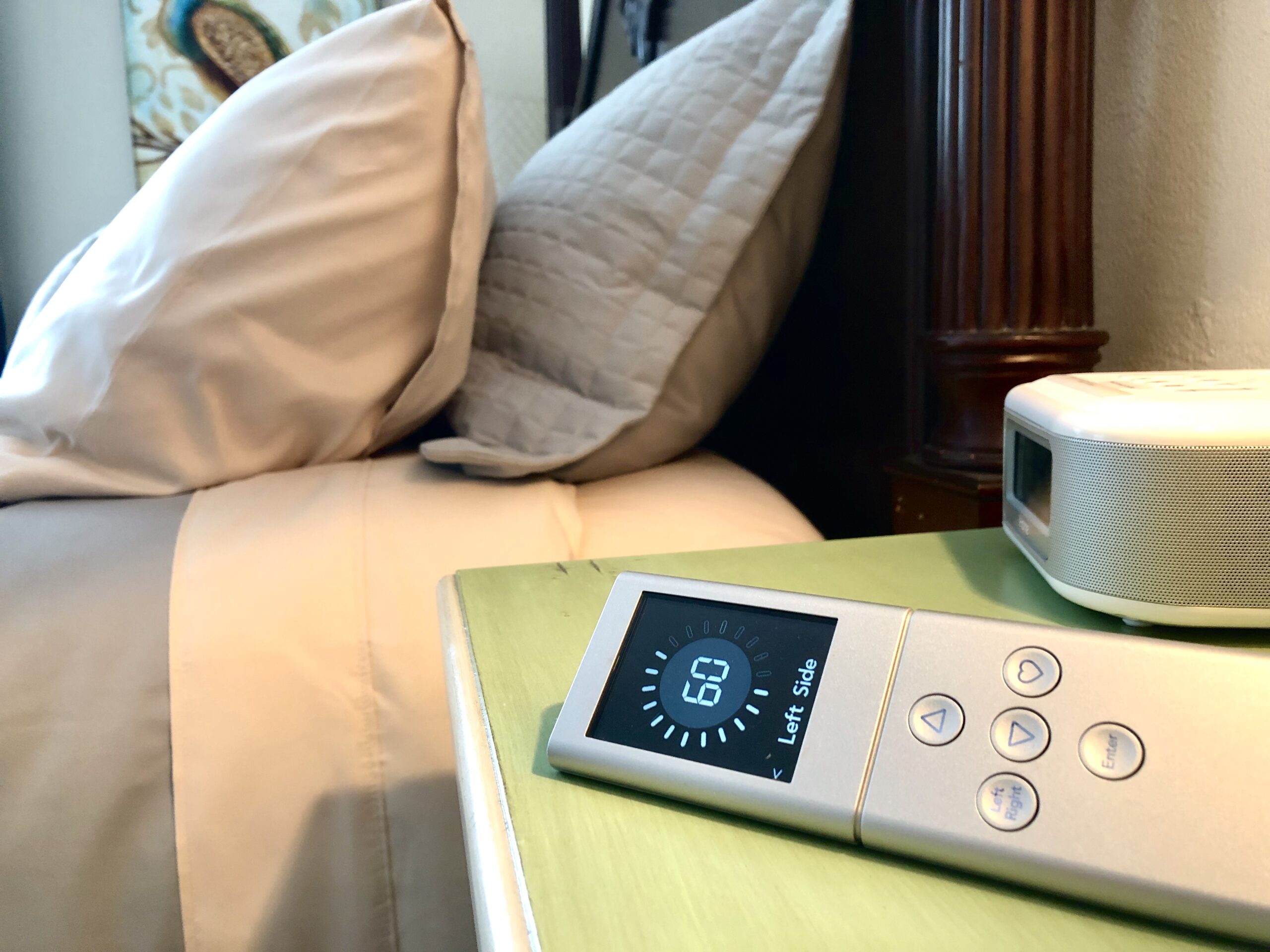 Sleep number bed in background with remote control in foreground to adjust firmness on each side.